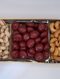 Three section tray filled with pistachios, chocolate covered cherries and cashews