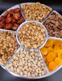 plums, cashews, mixed nuts, pistachios, apricots, macadamia nuts, and praline pecans displayed in a platter