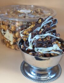 Gourmet chocolate covered caramel popcorn and nuts in a silver bowl