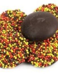 Round disks of chocolate topped with colorful nonpareils in orange, brown, and yellow.
